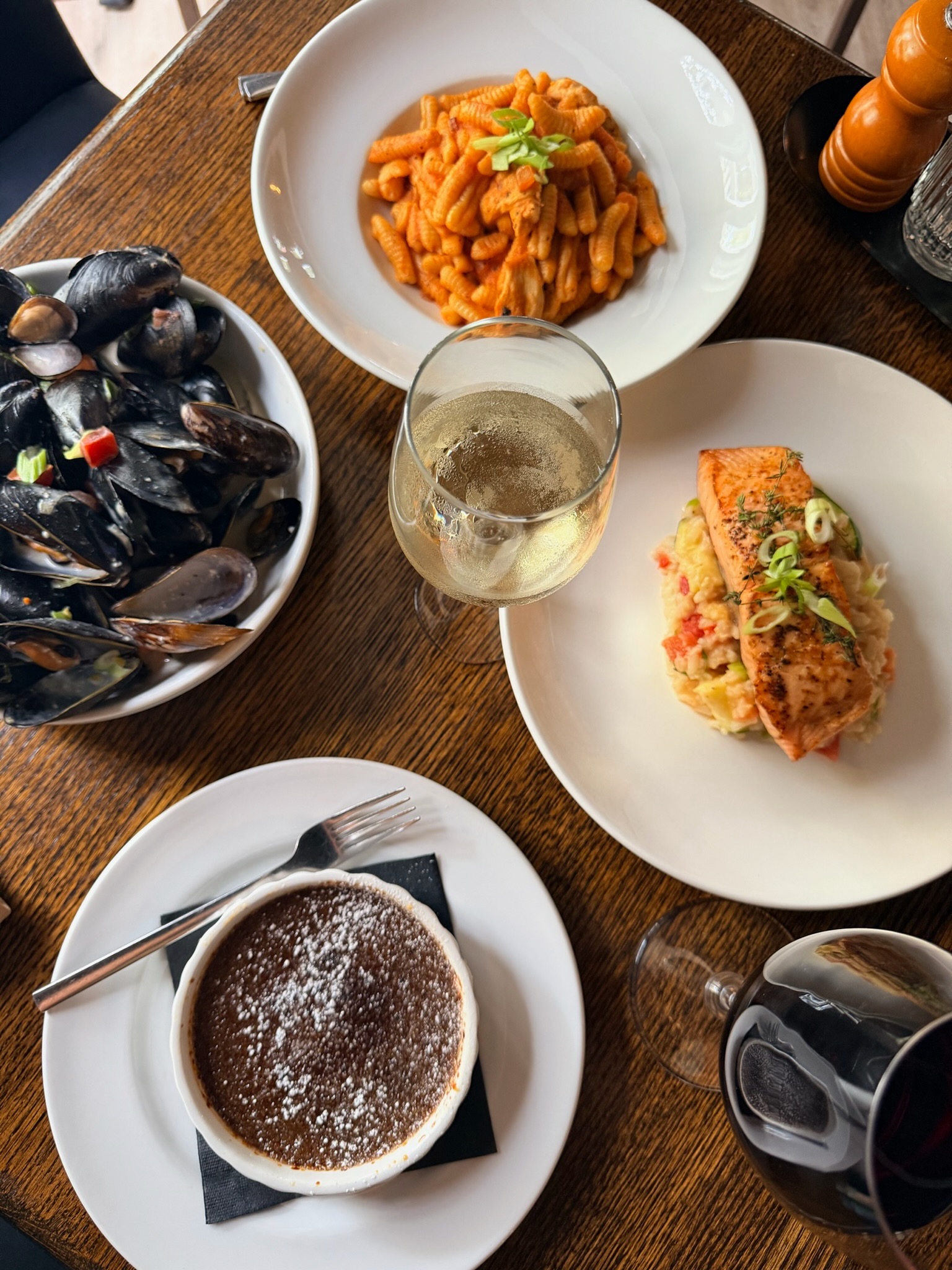 A shared Vinea table with mussels, pasta, salmon, dessert, and wine